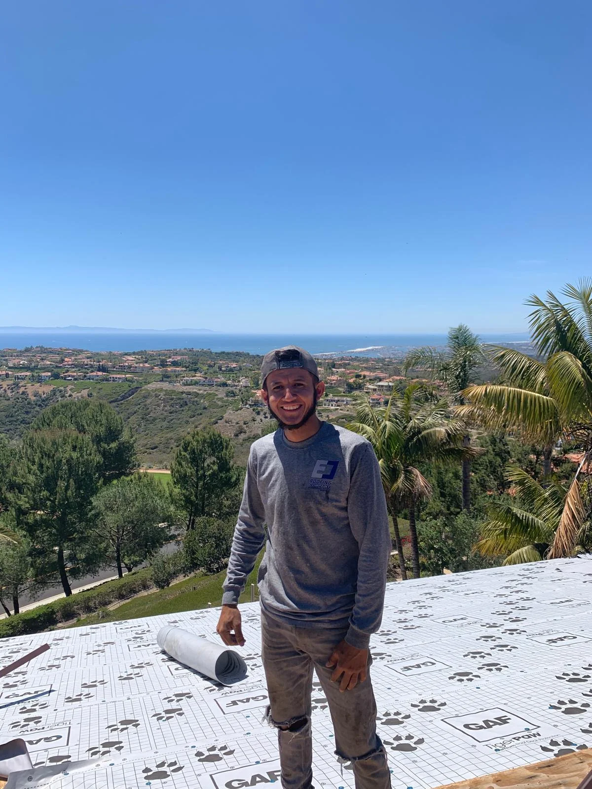 GAF roofing underlayment installation on residential roof with ocean view backdrop